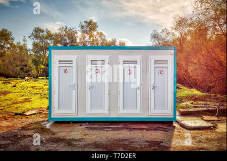 Prefabricated portable cabin with four numbered doors on a meadow field in the forest Stock Photo