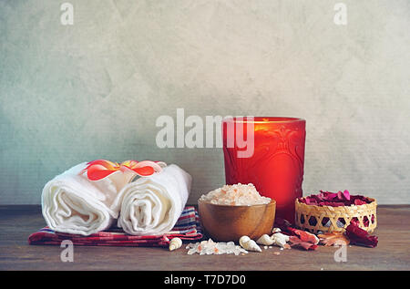 Himalayan salt with towel and aroma candle decorate with dry roses on wood table for scrub spa therapy. Stock Photo