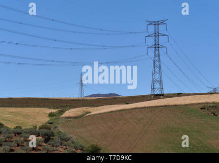 Shadows cast by the suspended Transmission cables from Pylons on the ground over Olive Trees and prepared Fields in Andalucia, Spain. Stock Photo