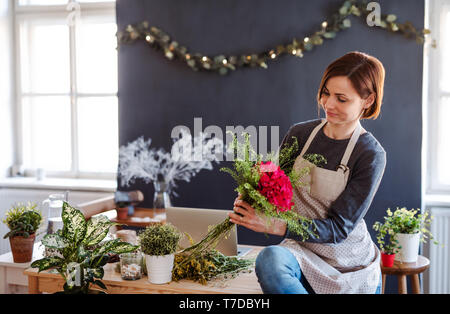 A young creative woman arranging flowers in a flower shop. A startup of florist business. Stock Photo