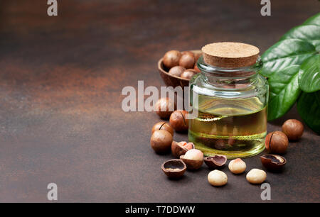 macadamia oil in a glass bottle, macadamia nuts on a brown background Stock Photo