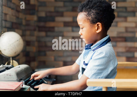 African American boy typing on typewriter in living room - curiousity and learning by doing for kid concept Stock Photo