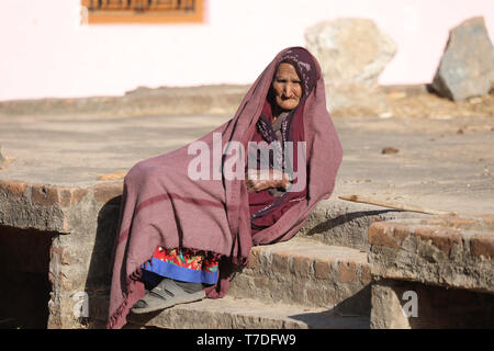 Old Woman sitting on street and looking Stock Photo