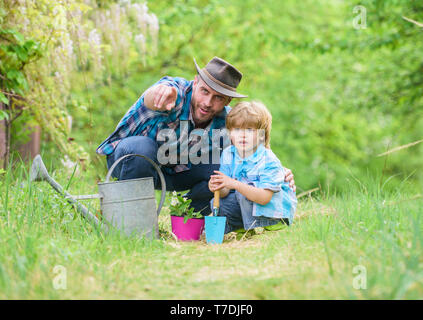 Take care of plants. Boy and father in nature with watering can. Gardening tools. Planting flowers. Dad teaching little son care plants. Little helper in garden. Make planet greener. Growing plants. Stock Photo