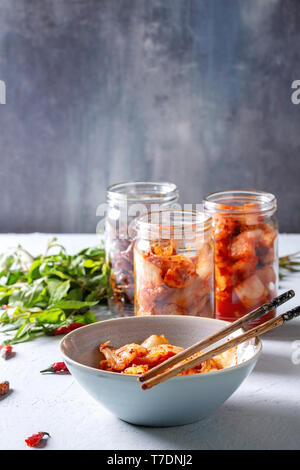 Korean traditional fermented appetizer kimchi cabbage and radish salad, hot spicy anchovies fish snack served in glass jars and bowl with Vietnamese o Stock Photo