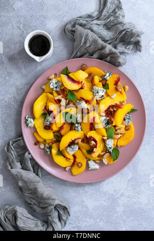 Peach salad, sliced peaches, blue vein cheese and mixed nuts with a jug of spicy dressing. Stock Photo