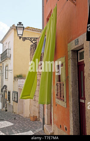 Lime green sheet washing hanging outside a colourful house in street in Alfama Lisbon Portugal Europe EU  KATHY DEWITT