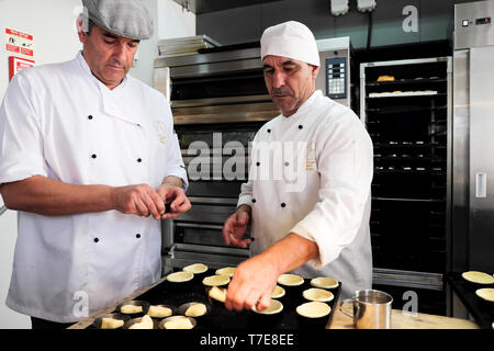 Two male employees working making pastry cases for traditional Pasteis de Nata Portuguese tarts inside a pastelaria in Alfama Lisbon  KATHY DEWITT Stock Photo