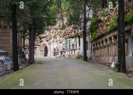 Perspective view of the curved footpath with graves and crypts on the Montjuic Cemetery in overcast day, Barcelona, Catalonia, Spain Stock Photo