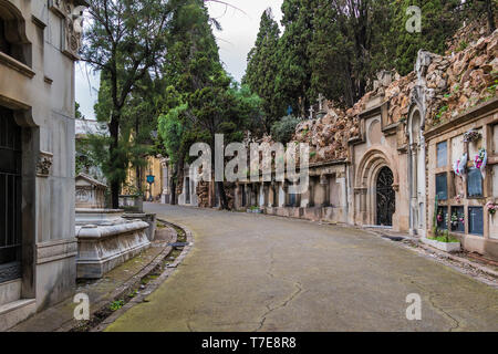 Perspective view of the curved footpath with graves and crypts on the Montjuic Cemetery in overcast day, Barcelona, Catalonia, Spain Stock Photo