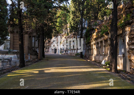 Perspective view of the curved footpath with graves and crypts on the Montjuic Cemetery in sunny day, Barcelona, Catalonia, Spain Stock Photo