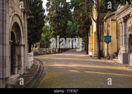 Perspective view of the curved footpath with graves and crypts on the Montjuic Cemetery in sunny day, Barcelona, Catalonia, Spain Stock Photo