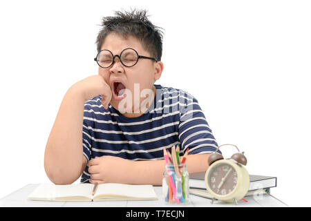 Tired student boy with glasses yawning on the table isolated on white background, education concept Stock Photo