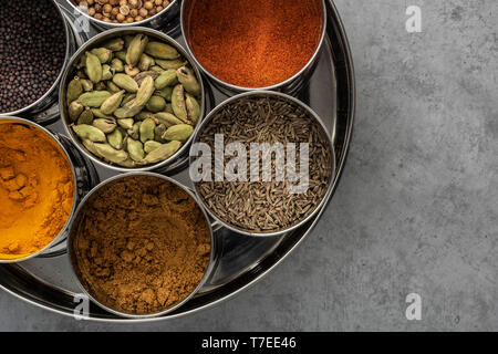 Indian Spice Tin (masala dabba) on cement background seen from above. Stock Photo
