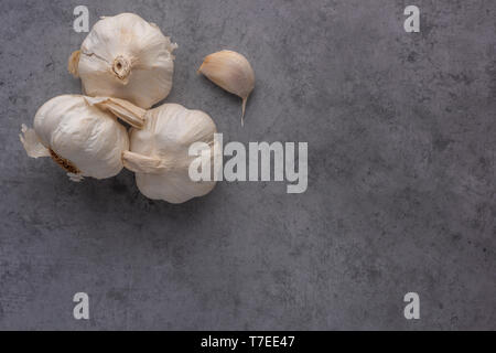 Garlic bulbs and clove on cement background seen from above. Stock Photo