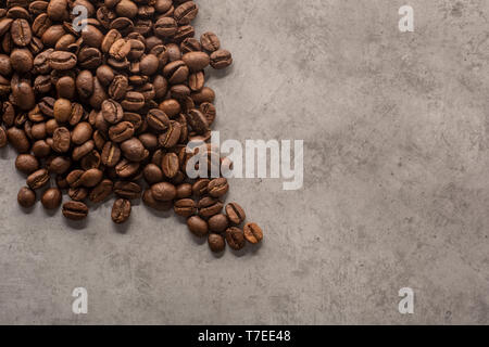 Roasted coffee beans on cement background seen from above. Stock Photo