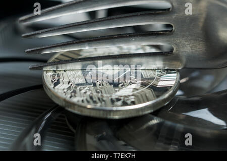 Monero cryptocurreny coin placed on GPU graphic card and fork trying to half it, hard fork Stock Photo