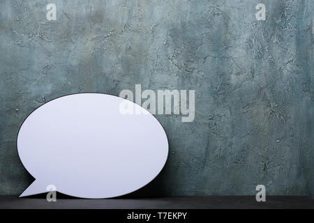 Speech Bubble lightbox on desk. Plastic light box in form of chat message icon with rustic background and copy space. Stock Photo