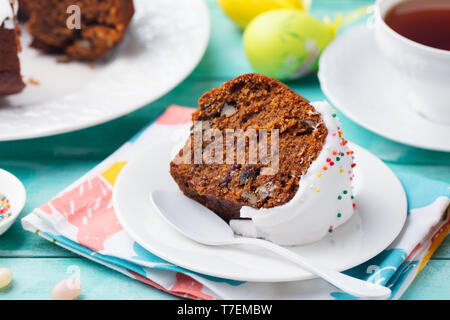 Easter cake on a white plate with colorful eggs. Blue wooden background. Close up. Stock Photo