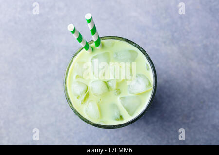 Matcha green tea ice latte in a glass. Grey stone background. Top view. Stock Photo