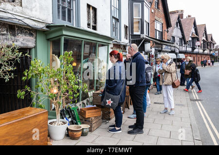 A middle aged couple looking in the window of an vintage antique shop with antiques surrounding the shop window Stock Photo