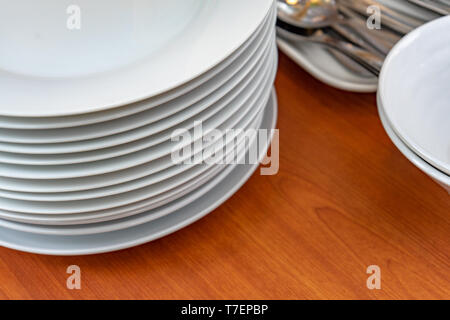 Dish, plates, bowls, spoon, fork are arranging and preparing on wood table for buffet lunch or dining., have space for text below. Stock Photo