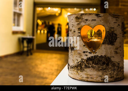 Candle behind the window in the middle of a log with people at the bar in the background. Stock Photo