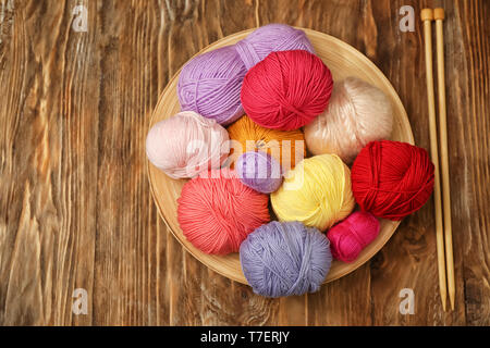 Colorful knitting yarns and needles on wooden table Stock Photo