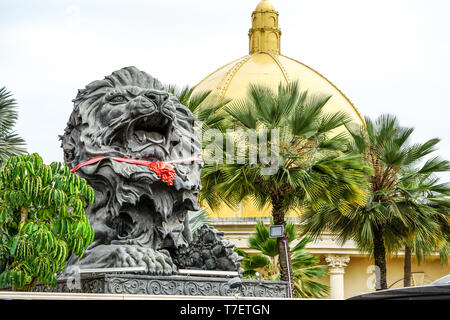 close up big black lion statue with red scarf sitting front of building., Laos. Stock Photo