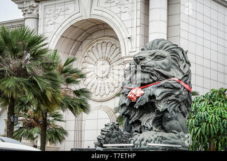 close up big black lion statue with red scarf sitting front of building., Laos. Stock Photo