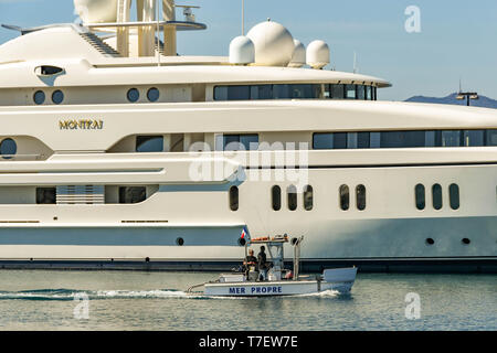 CANNES, FRANCE - APRIL 2019: The superyacht Montkaj berthed in the Port Pierre Canto harbour in Cannes. A small 'Clean Sea' motor boat is passing Stock Photo