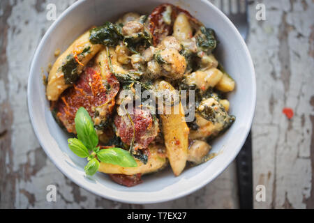 Potato dumplings, spinach, sun dried tomatoes and courgette in cheese sauce Stock Photo