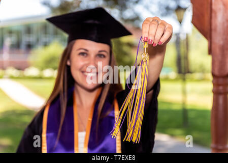 Beautiful young female student smile while holding class of 2019 tassel out in front. Stock Photo