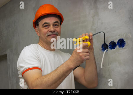 Cheerful elderly electrician working on the repair of the apartment Stock Photo