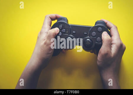 Gamer hands holding gamepad. Gaming concept. Retro styled gamepad from 90s. Stock Photo