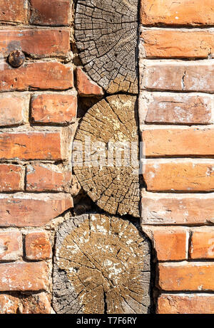 Vintage red brick wall with wooden logs as background Stock Photo