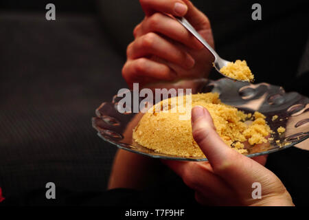 Eating Semolina helva dessert eating close up view in the glass dish Stock Photo