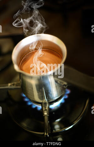 Turkish coffee cooking in the traditional pot on the oven Stock Photo