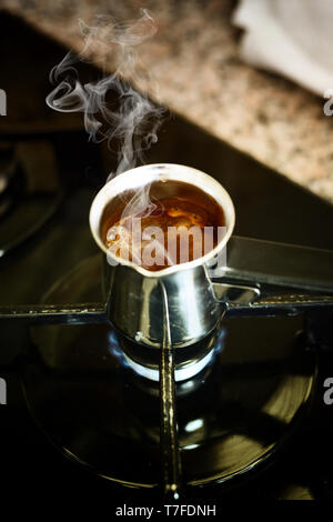 Turkish coffee cooking in the traditional pot on the oven Stock Photo