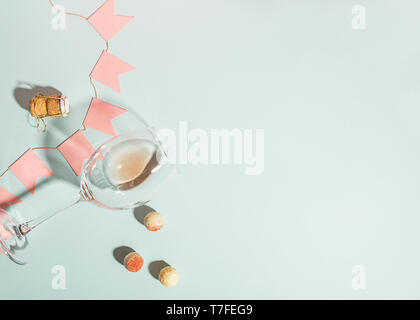Various white chocolate candies and a glass of champagne lie on a blue background with festive pink flags a garland. Stock Photo