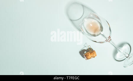 A glass with a drink and a bottle cork is lying on an empty blue background. Flat lay. View from above. Copy space . Stock Photo