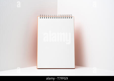 Design concept - perspective view of orange spiral notebook, white page on white 3D space background for mockup, it's real photo, not 3D render Stock Photo