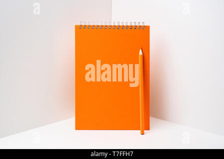 Design concept - perspective view of orange spiral notebook, white page on white 3D space background for mockup, it's real photo, not 3D render Stock Photo