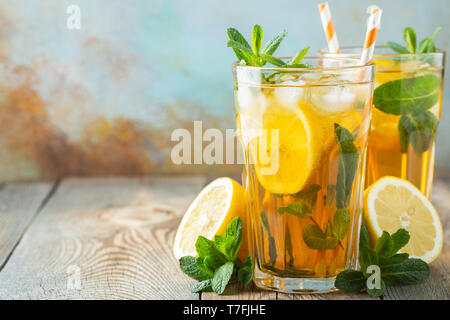 Traditional iced tea with lemon and ice in tall glasses on a wooden rustic table. With copy space. Stock Photo