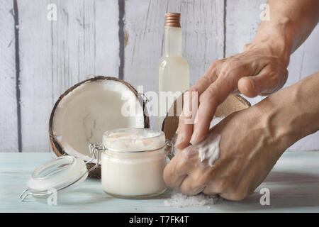Human hands smearing cream. Homemade cream made of coconut and roses, in a glass jar Stock Photo