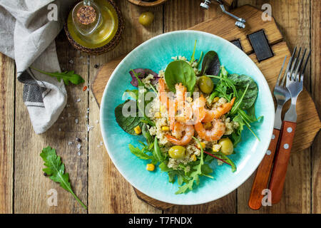Diet menu, Vegan food. Healthy salad with quinoa, arugula, Shrimps and olives on a wooden rustic table. Top view flat lay background. Stock Photo
