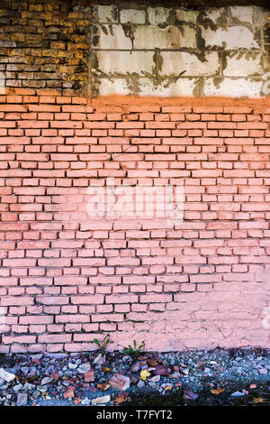 Yellow brick wall, part painted in pink, background with a ground Stock Photo