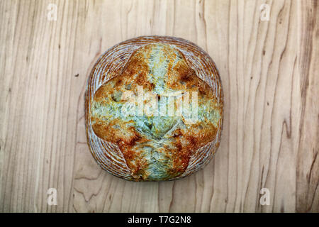 Artisan crusty loaf of freshly baked sourdough bread focaccia boule. traditional Homemade sourdough Boule bread with crust on a wooden board Stock Photo