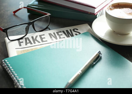 Newspaper with notebook and cup of coffee on table Stock Photo