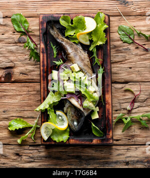 Baked trout with avocado on a wooden kitchen board.Baked fish with lettuce and avacado Stock Photo